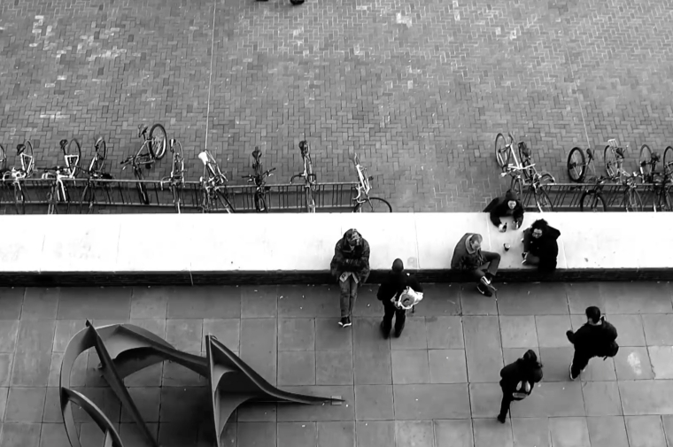 Still from the video showing people sitting on plaza