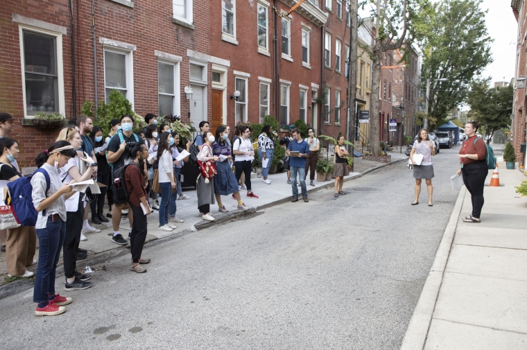group of students stand on street of rowhouses