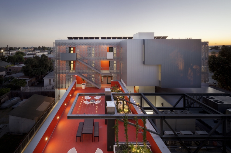 Cuboid apartment block with red-surfaced terrace