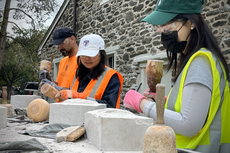 students in high visibility vests carving blocks of stone