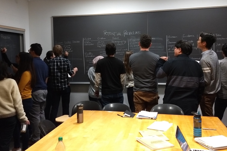 students gathered around blackboard