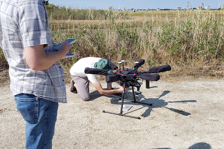 A man works on a small drone with a man standing next to him