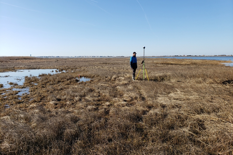 A man standing next to a tall monitor in a wetland