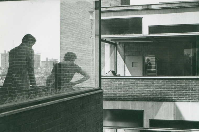 People peering through window of modernist building