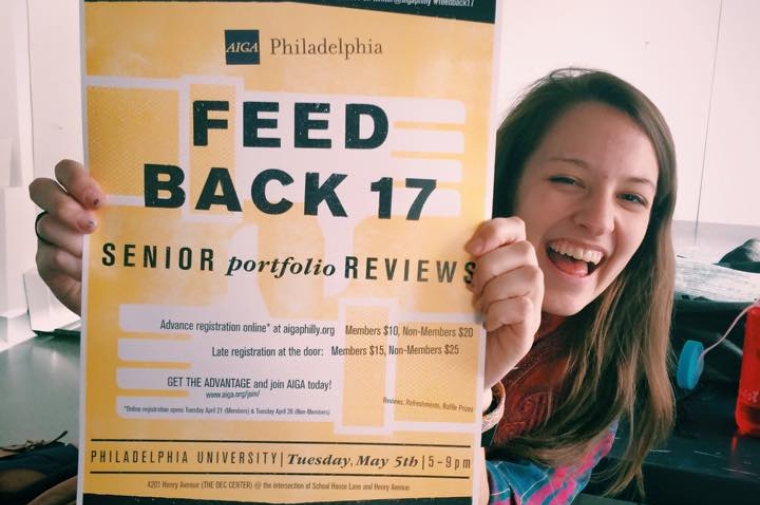 Student holding poster saying "Feed Back 17, Senior Portfolio Reviews