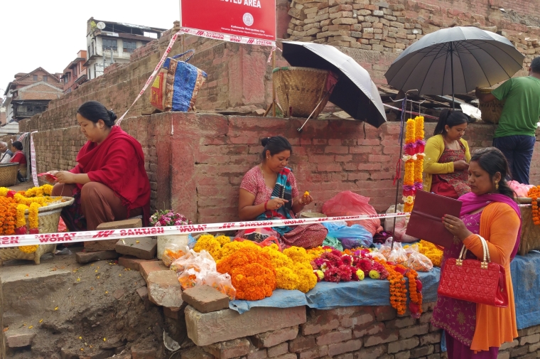 Women stringing brightly colored flowers