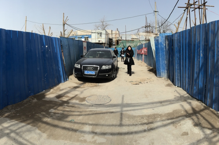 Tin walled walkway with car and pedestrians
