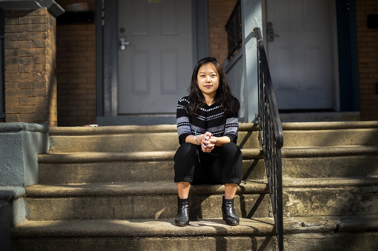 Lily Cheng sitting on the steps going up to the front porch of her house