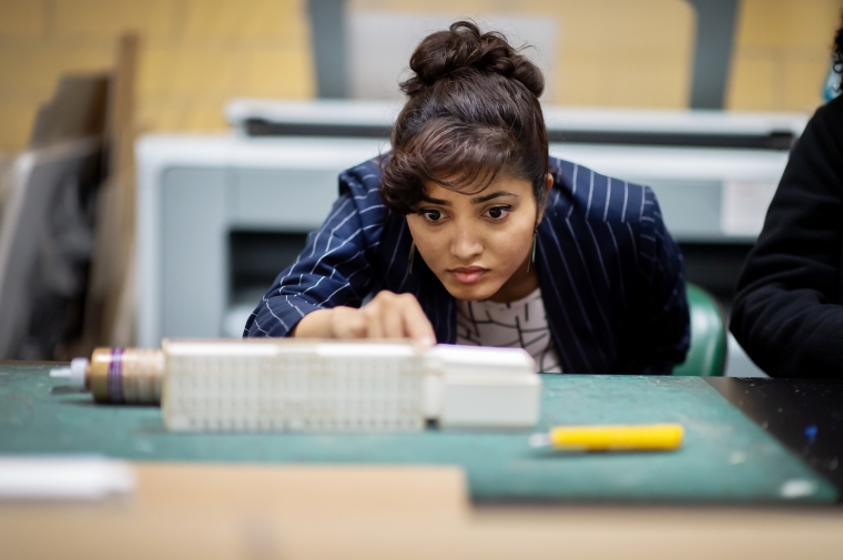 A person leans over to take a close look at an architectural model