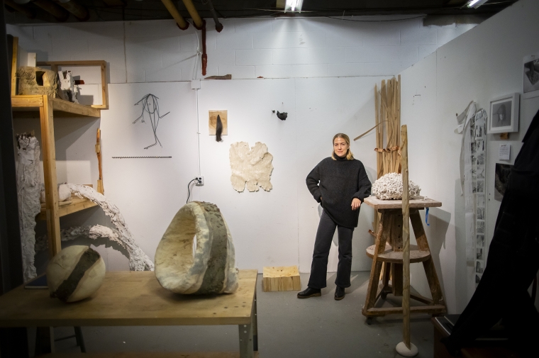 A fine arts student poses in their studio space