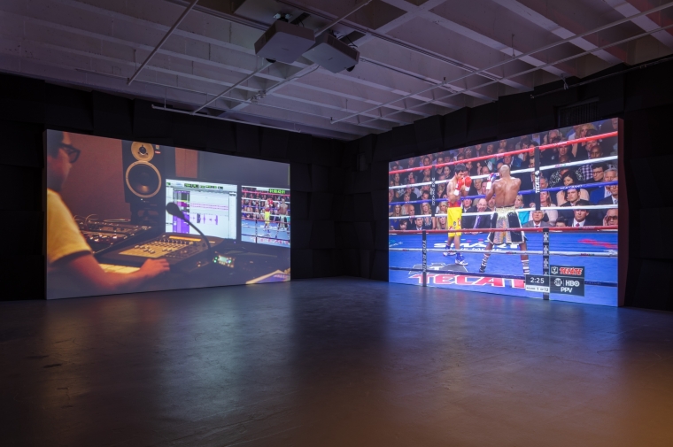 Videos play on two screens in darkened gallery