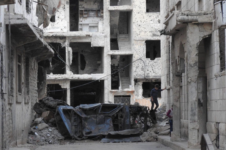 A boy crossing a street divided by rubble