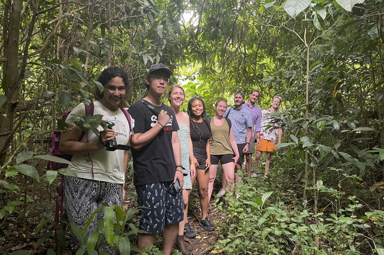 A group of people pose in a line in lush tropical scenery
