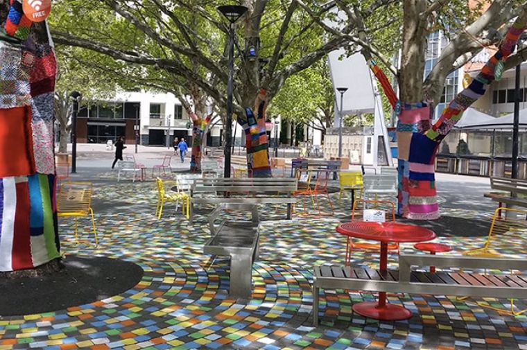 Highly decorated park space. Tree trunks are covered with knitted craft.