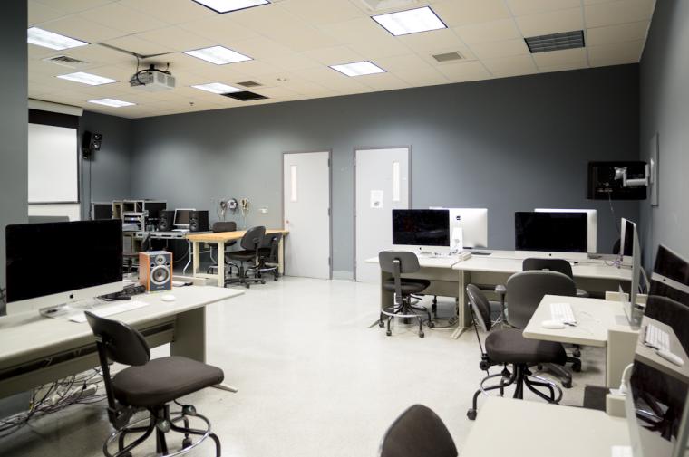 Brightly lit unoccupied computer lab with screen and projector