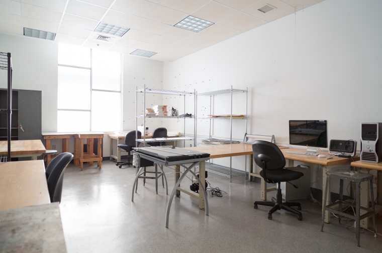 Unoccupied office/studio space with several computers and a work table in the center.