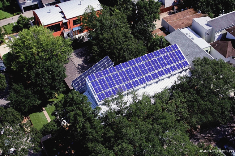 Solar panels cover a rectangular building surrounded by trees