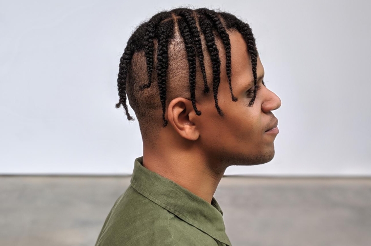 side profile of american artist, with the background floor and wall meeting right under the chin