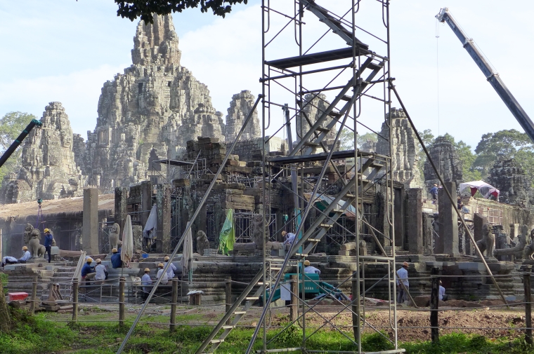  Workers in hard hats operate machinery at a stone temple