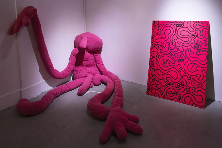 A pink soft sculpture sits on concrete floor next to pink painting