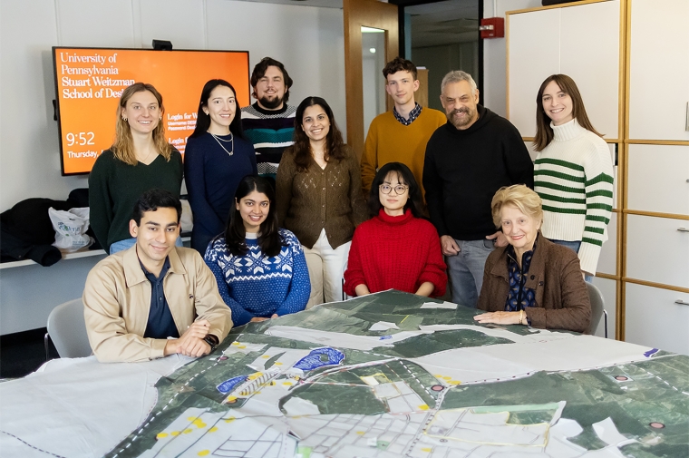 A group of people pose behind a large map on a table