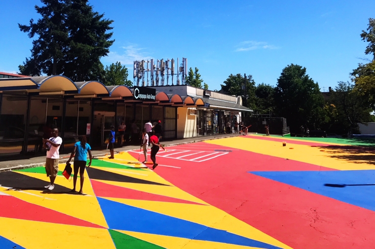 Walkway painted with triangles in primary colors with people walking on it