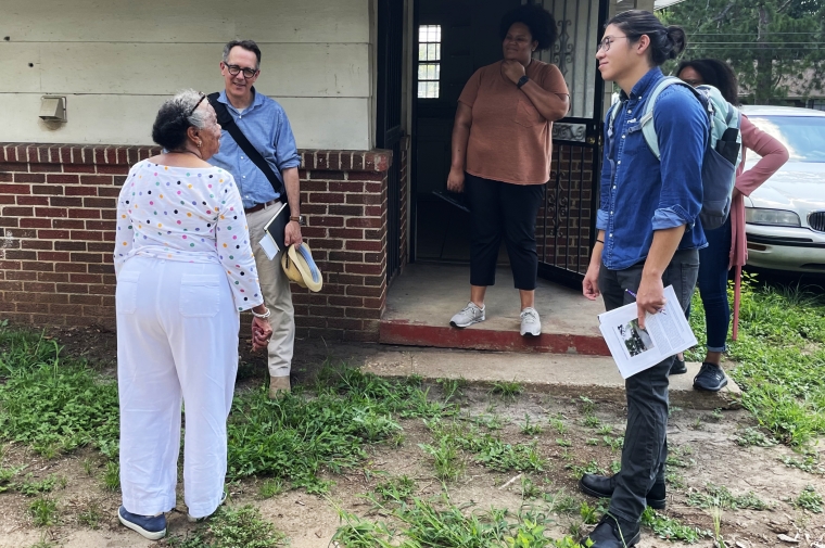 A group of people chatting outside a home