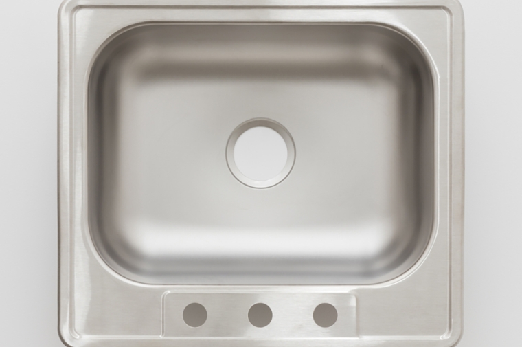 A stainless steel sink hung upside down on a white wall.