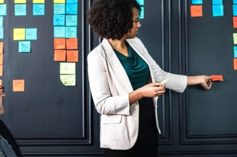 Colleagues putting sticky notes up on a board