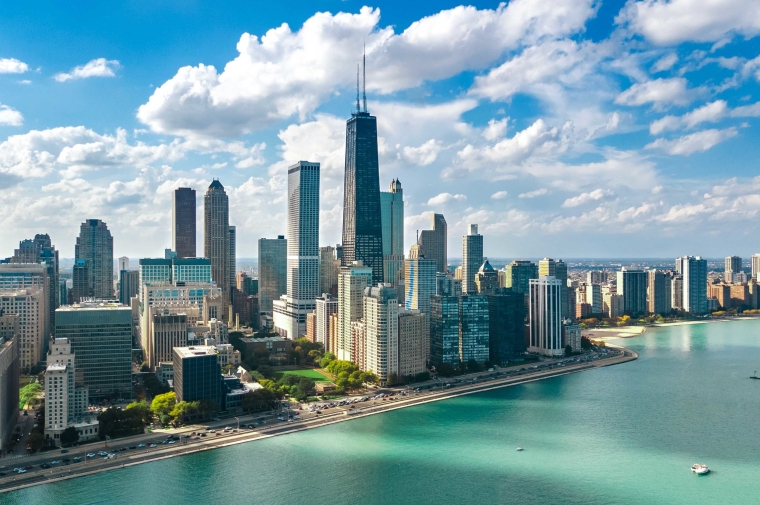 Chicago skyline with tall buildings, sunny skies, and water with boats