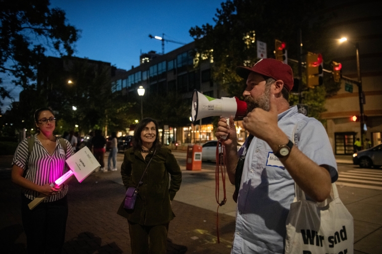 Man with bullhorn leads crowd outdoors