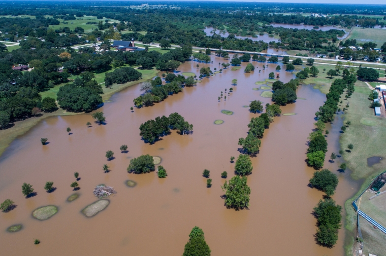 Aerial view above muddy brown river overflowing its banks