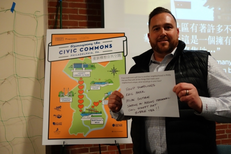 Participant holding up exchange while standing in front of event sign.