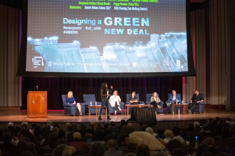 Six people seated on a stage in front of a screen at GND event