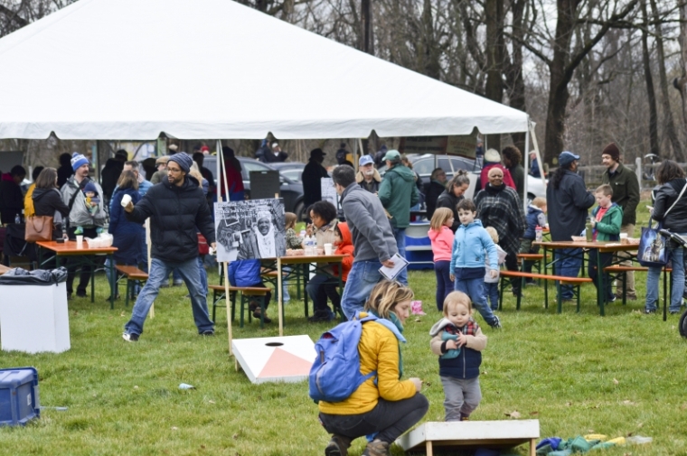 Community members gathered around tables and under the tent.