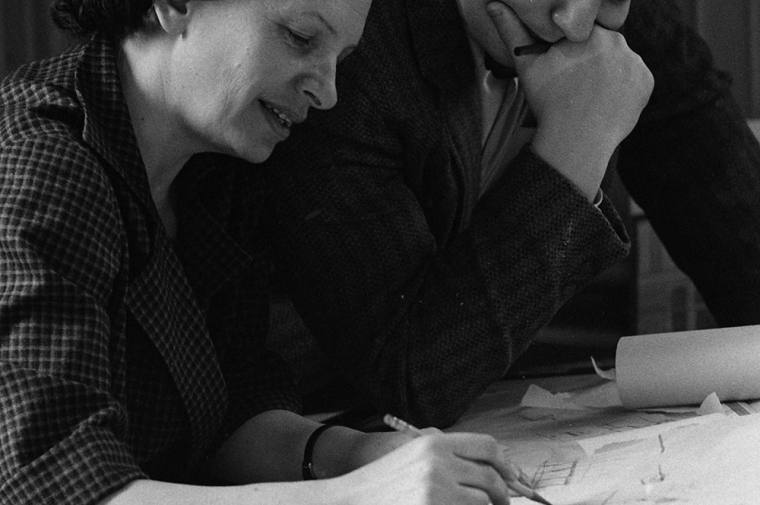 A man watches a woman drawing