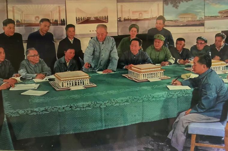 A meeting of Chinese officials at a long table with architectural models on display