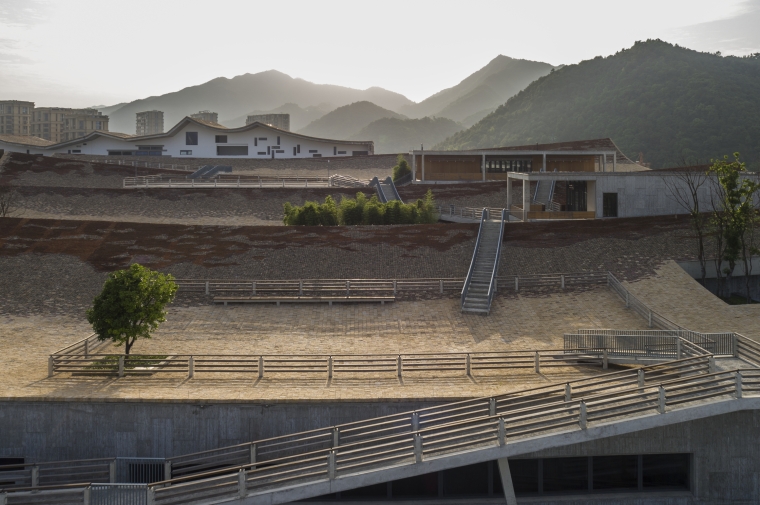 Low-slung wood and concrete structures punctuate a terraced hillside with ramps
