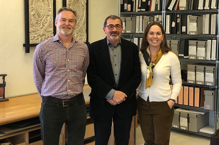 A group of three people in front of a library wall