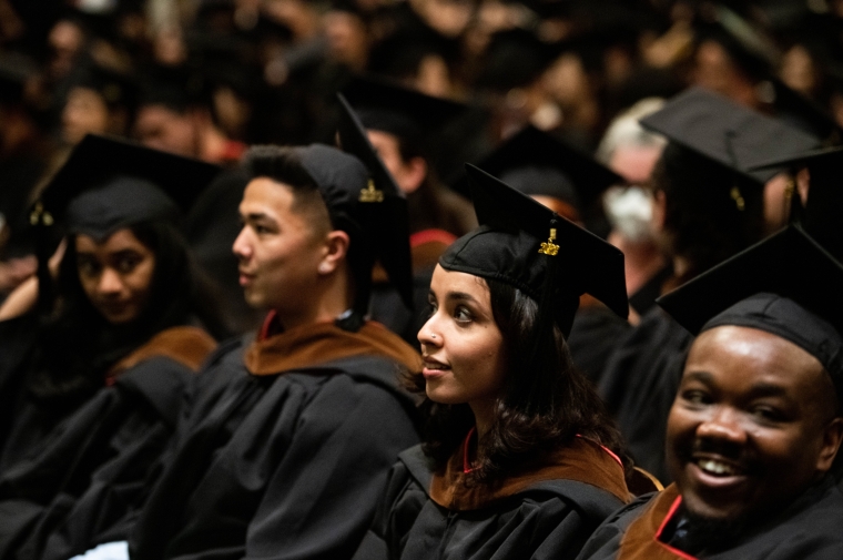 Young people in black cap and gown seated 