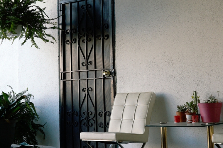 A white chair sits next to a black metal door