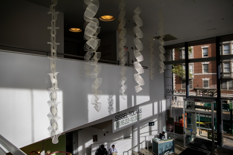 A white wall behind strips suspended from ceiling leads to window on street