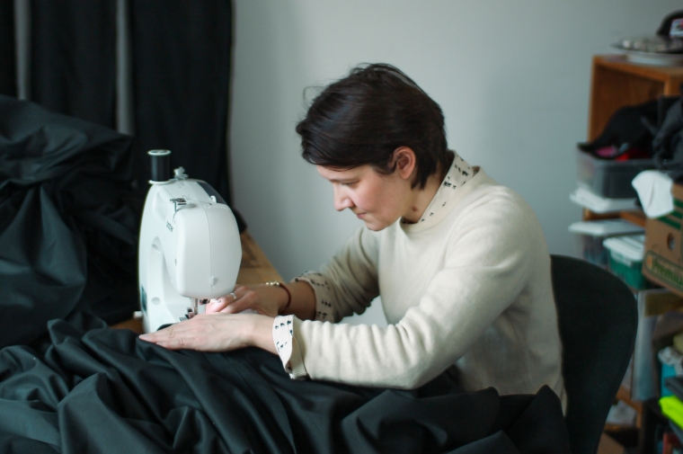 Aislinn working with black fabric at a sewing machine