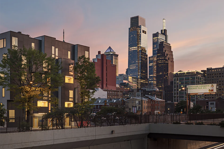 Sleek 6-story housing complex with Philadelphia skyline in background