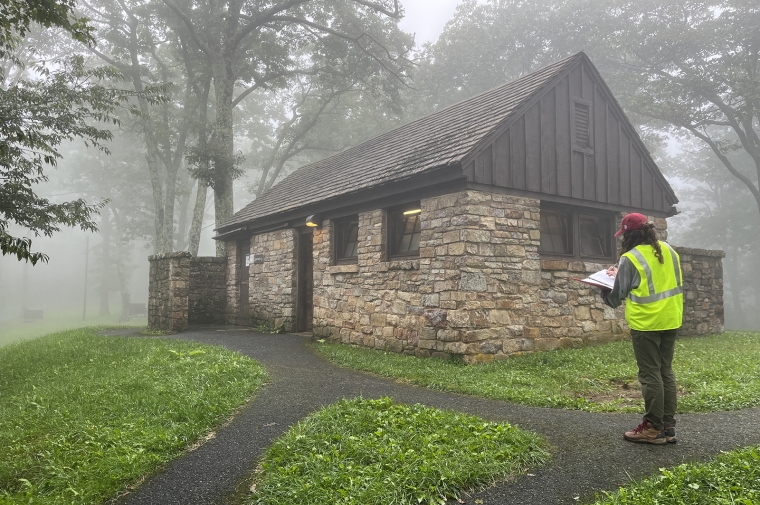 figure in yellow safety jacket in front of stone building