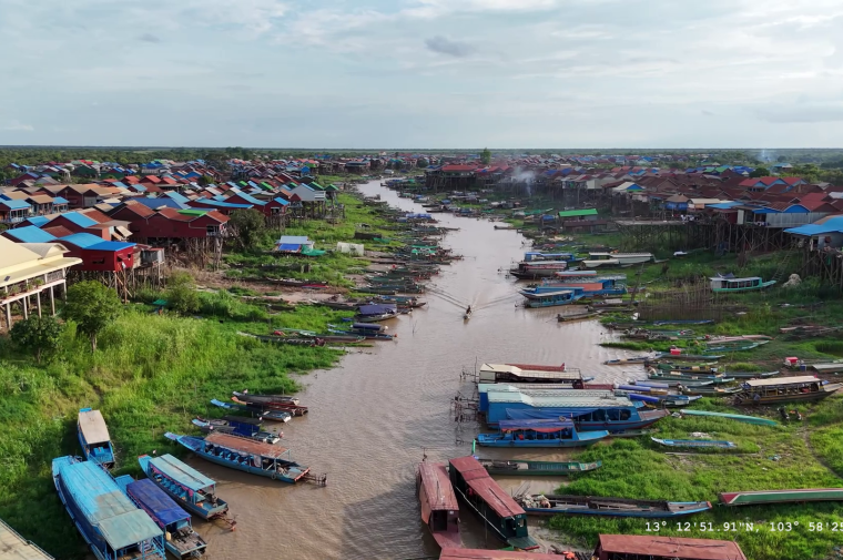 riverfront houses and fishing boats along a stream in Cambodia