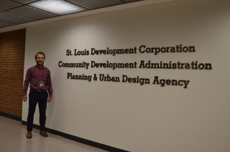 Andrew Knop standing next to St. Louis Development Corporation sign