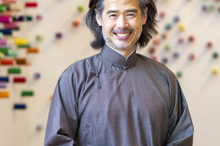 portrait of Mingwei with his colorful dotted artwork out of focus in the background