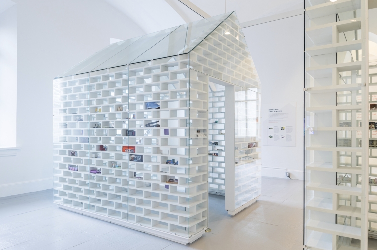 A white perforated-wall structure inspired by a Cape Code home in a museum gallery