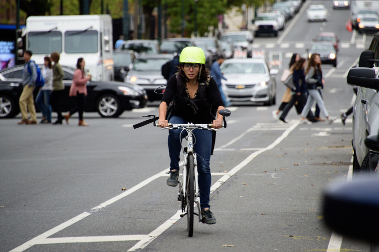 Megan Ryerson wears a helmet outfitted with clear eye-tracking glasses as she travels in a bike lane on a Philly street